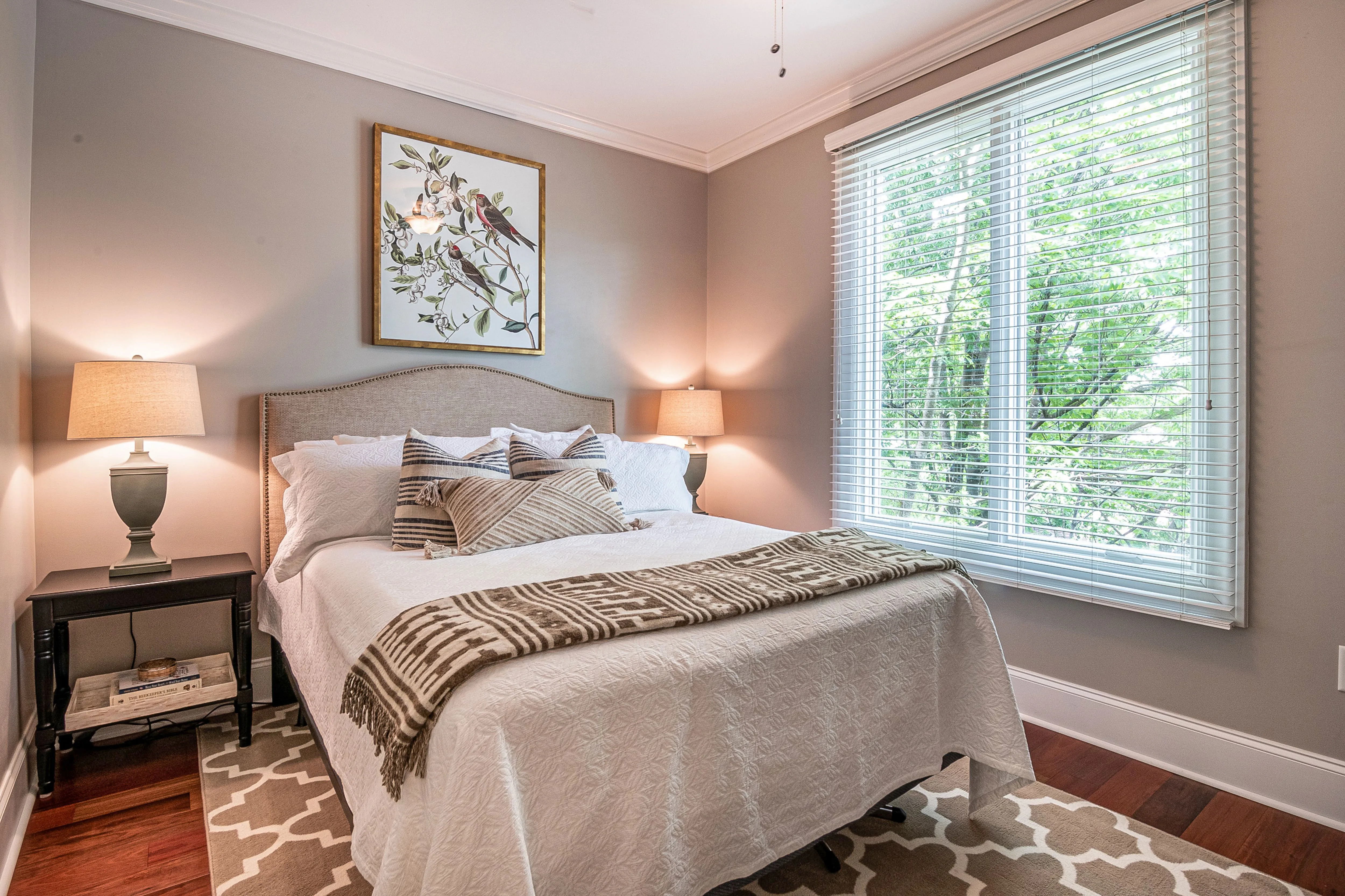Soft grey bedroom with bird artwork, warm wood floors, and neutral textured bedding