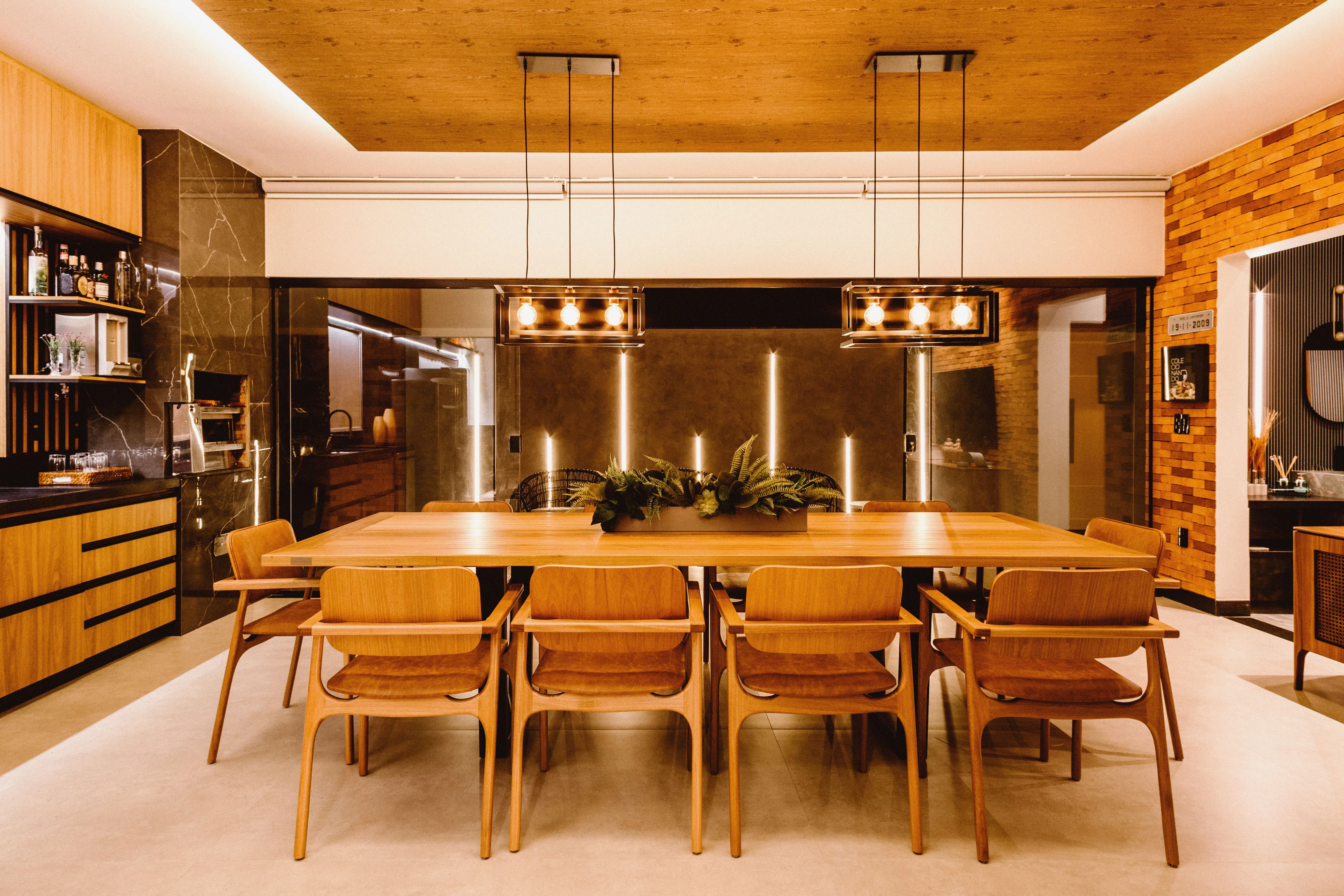 Modern kitchen with warm wood cabinetry, stainless steel refrigerator, and dark marble walls