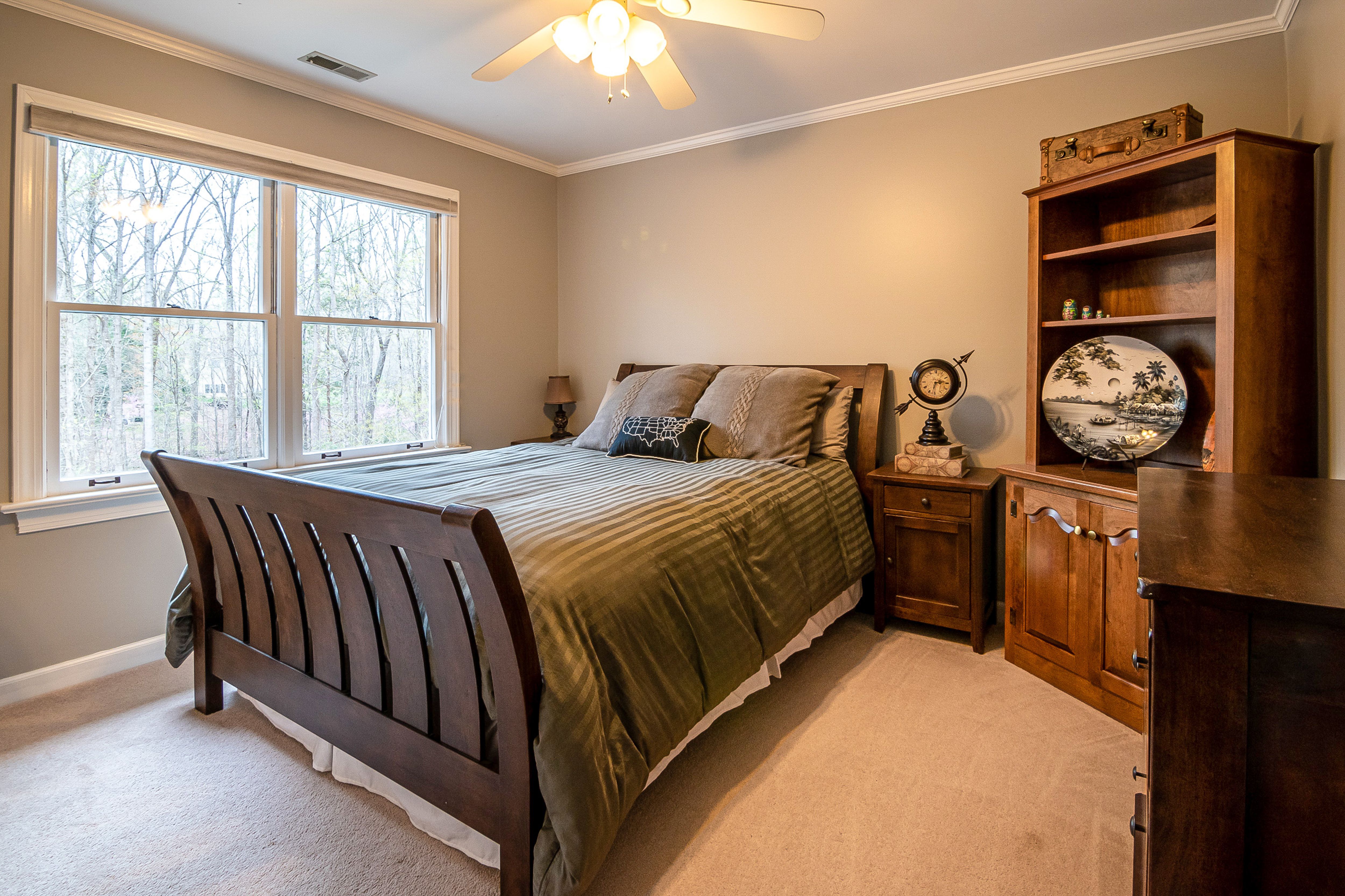 Traditional wood bedroom with green bedding, a globe, and a decorative plate on a bookshelf