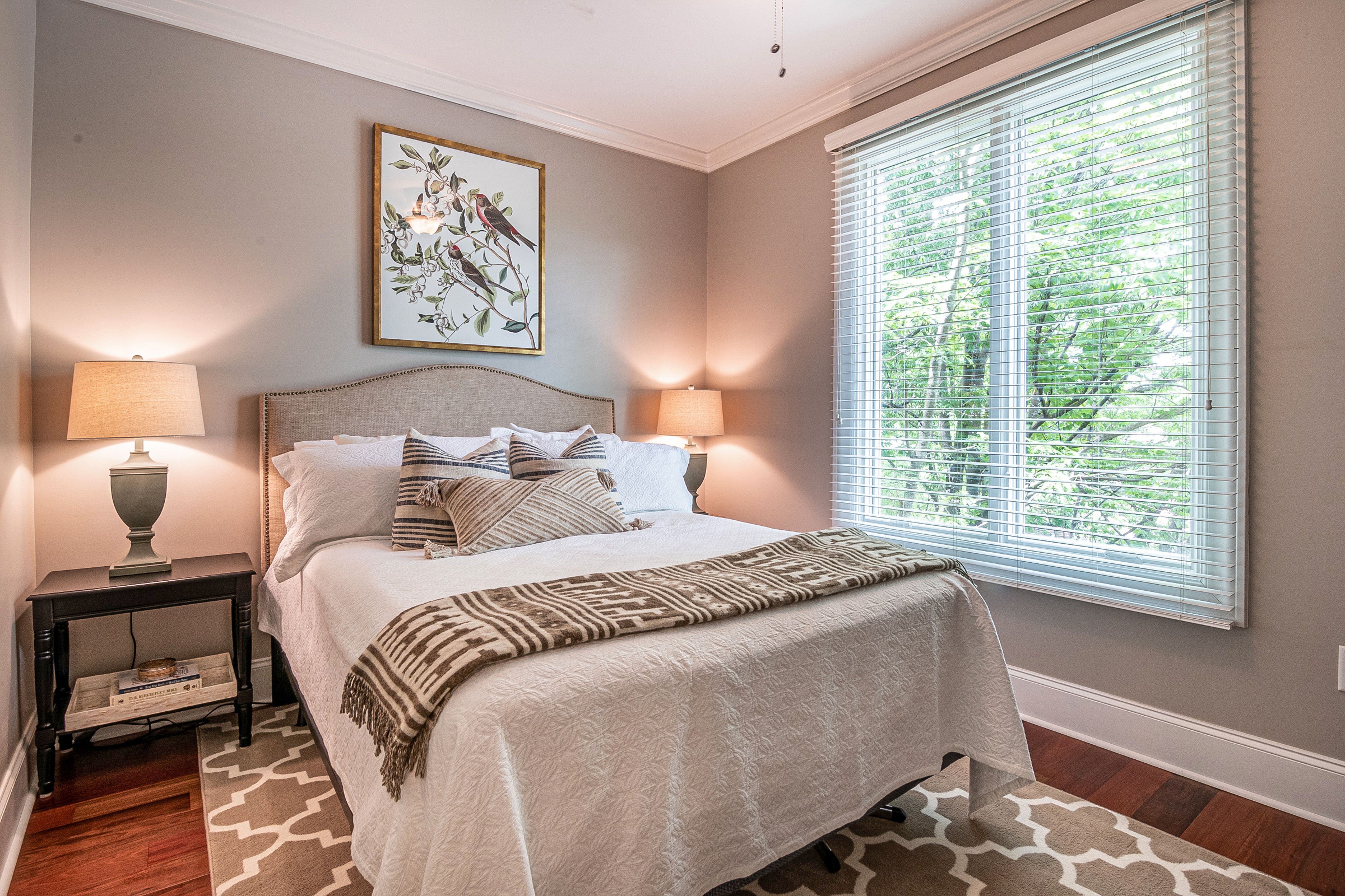 Soft grey bedroom with bird artwork, warm wood floors, and neutral textured bedding