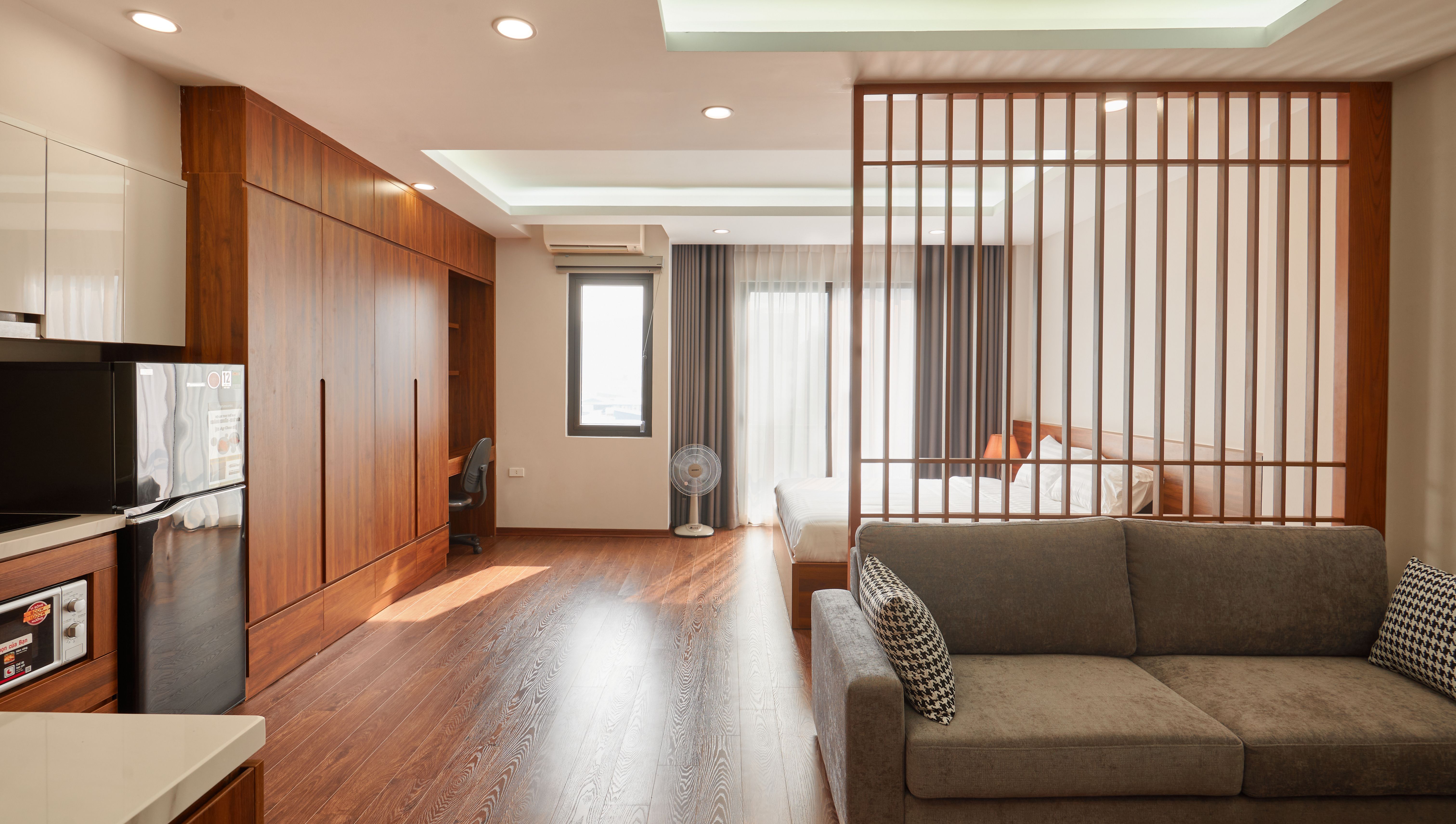 A modern studio apartment with a warm wood slat room divider separating the sleeping area from the living space
