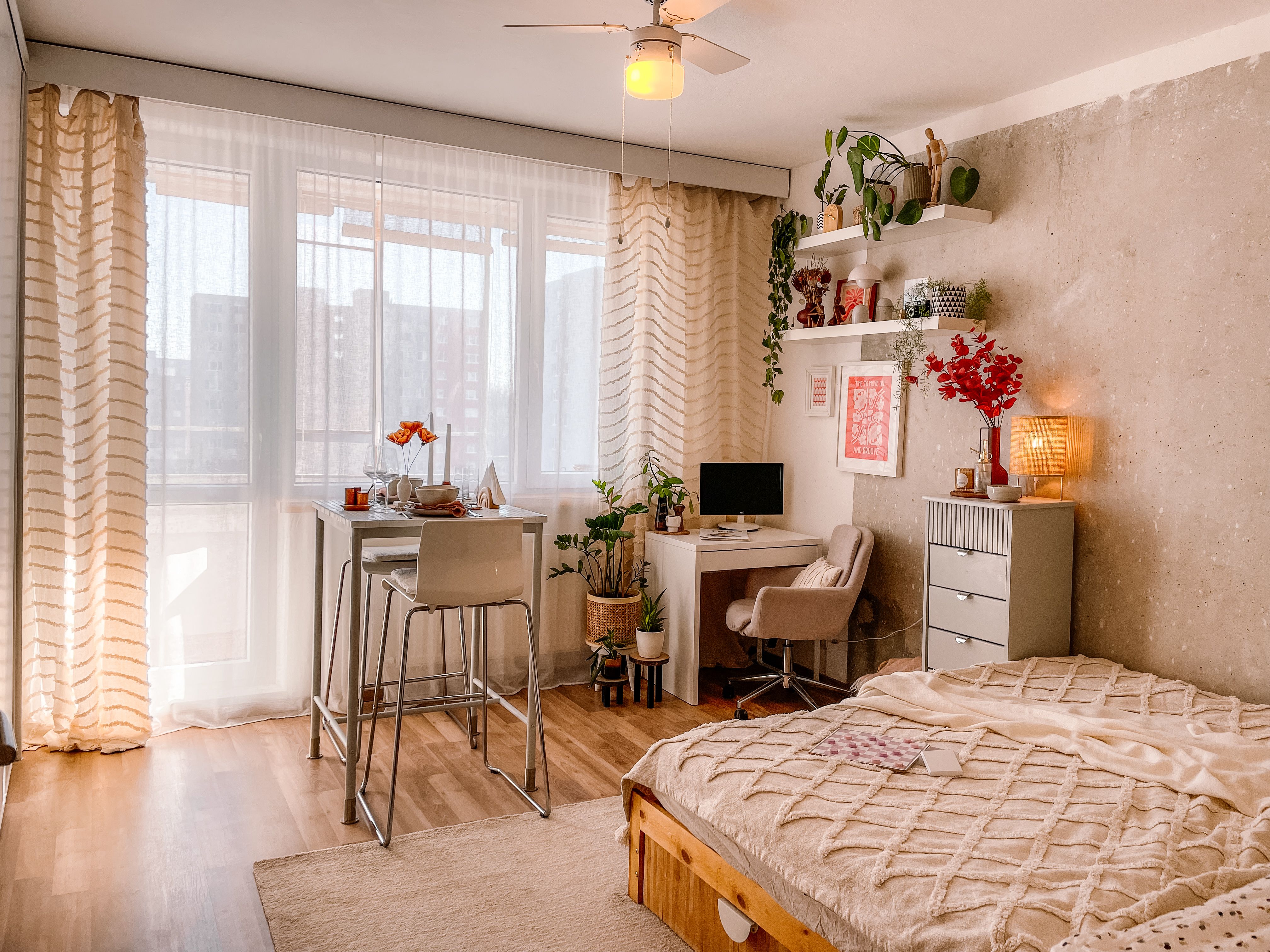 A warm studio apartment with bed, desk, and dining zones arranged in one cozy open room
