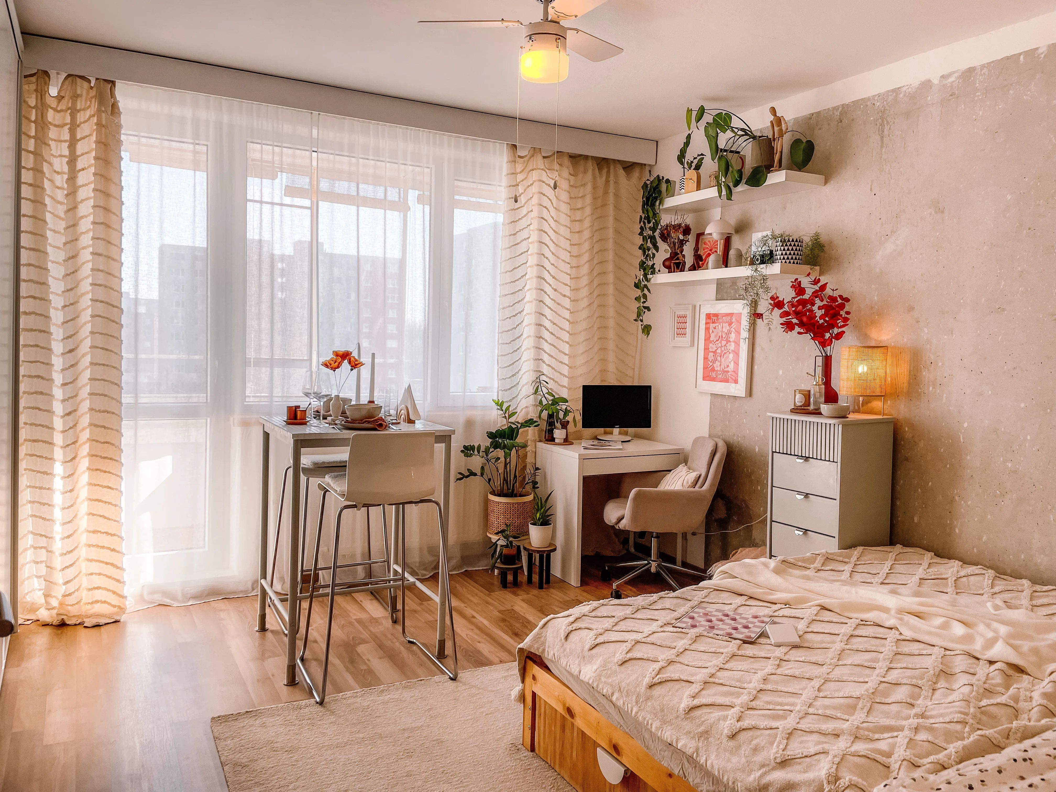 A warm studio apartment with bed, desk, and dining zones arranged in one cozy open room
